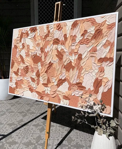 Abstract textured artwork on a white canvas with a wooden easel outdoors.
