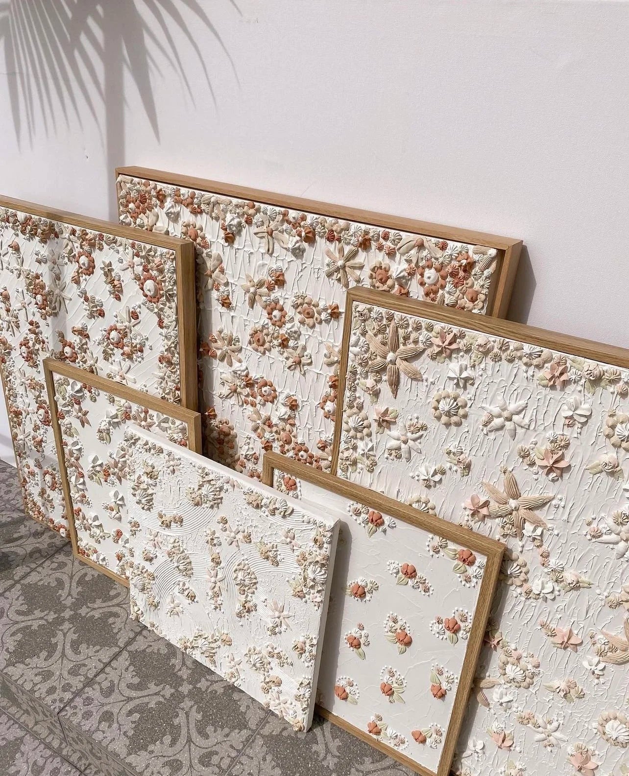 Set of floral-patterned textured artwork with wooden frames on a light background