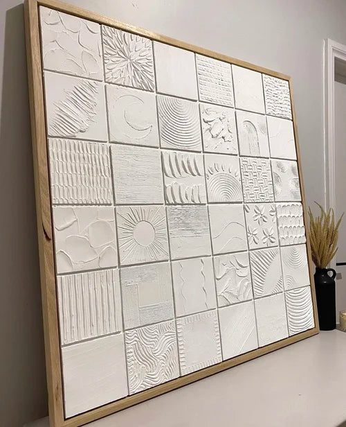 Framed textured artwork with embossed patterns on a white surface