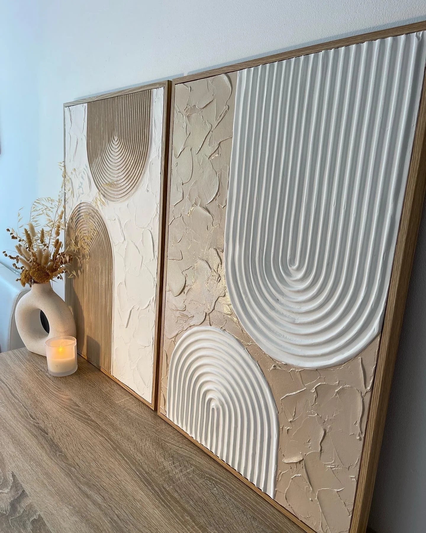 Textured artwork with textured patterns on a wooden shelf.