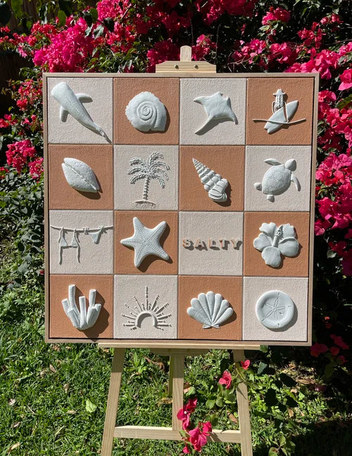 Textured artwork with designs on a wooden board against a floral background