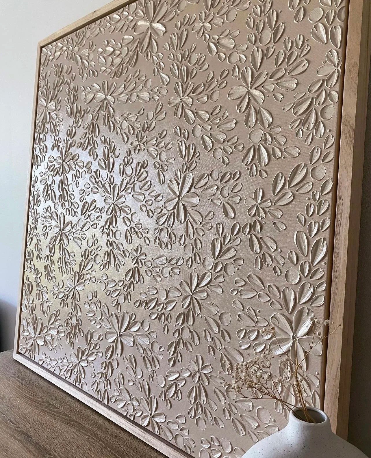 Textured artwork with floral pattern in a wooden frame.