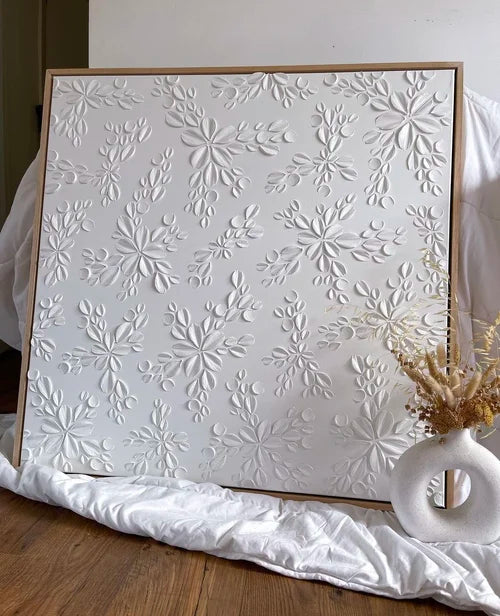 White textured art with floral patterns on a wooden floor.