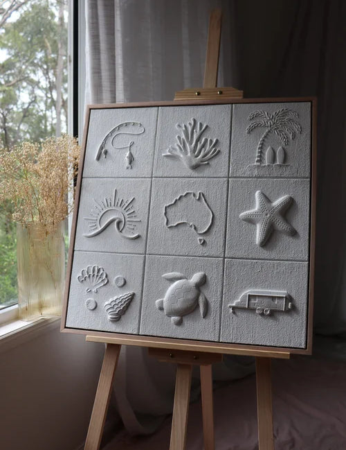Easel with embossed clay artwork featuring various designs on a neutral background.