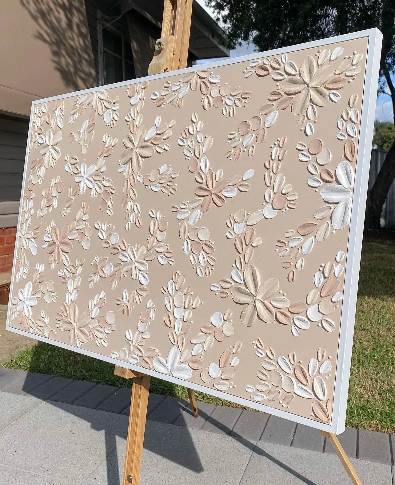 textured artwork with floral pattern on an easel outdoors